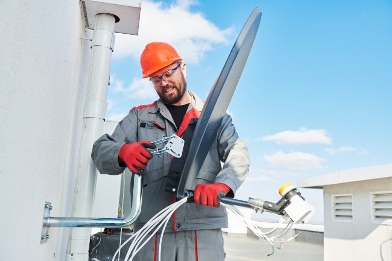 A man in an orange helmet is installing a TV antenna